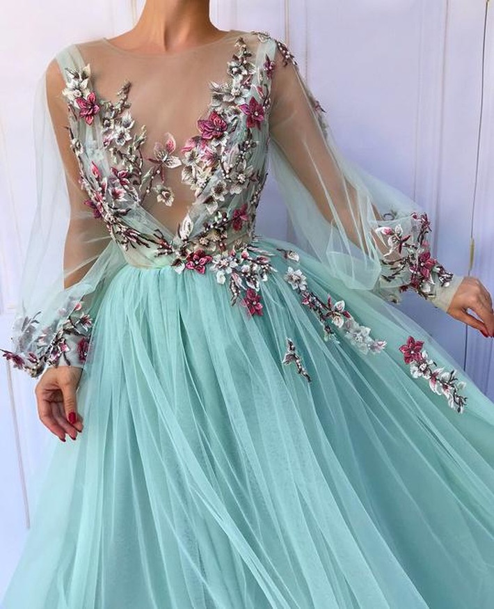 Chiếc đầm xanh thêu hoa đỏ tím nổi bật.