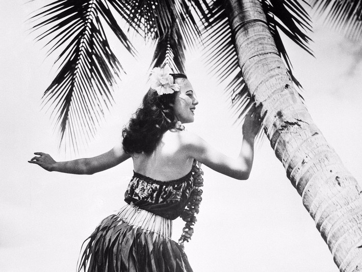 Năm 1955: Nữ vũ công mặc váy đan từ lá cây biểu diễn điệu nhảy Hula truyền thống trên biển Hawaii. Ảnh: Getty.