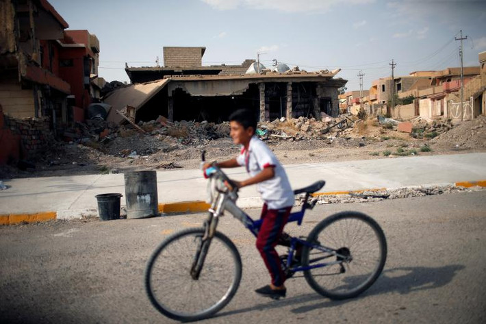 Một cậu bé Yazidi đạp xe qua khu nhà bị phá hủy trong khu vực Sinjar. Hiện nay, rất nhiều khu vực ở Sinjar vẫn còn hoang tàn sau cuộc thảm sát kinh hoàng 3 năm trước. Tuy nhiên, khoảng 1.000 gia đình Yazidi đã trở lại Sinjar kể từ khi thành phố được giải phóng vào năm 2015. Thành phố Sinjar và khu vực xung quanh đã có khoảng 400.000 người Yazidi. Ảnh: Reuters.