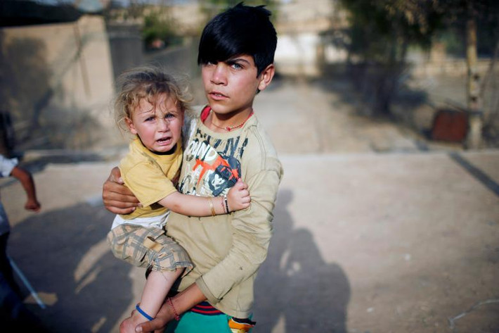Cậu bé Yazidi đang bế em gái mình trong một sân chơi ở khu vực Sinjar, Iraq. Tộc người Yazidi ở Iraq đang tưởng nhớ lại sự kiện phiến quân IS đã đánh chiếm thành phố Sinjar vào tháng 8/2014 và tiến hành nhiều vụ thảm sát những người Yazidi sống ở đó. Liên Hợp Quốc đã mô tả các vụ phiến quân thảm sát người Yazidi ở Iraq là tội ác diệt chủng. Ảnh: Reuters.
