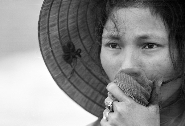 Người phụ nữ dùng khăn che miệng, gương mặt lộ rõ vẻ lo âu khi đứng trước một ngôi mộ tập thể được khai quật tại làng Điện Bàn ở phía đông thành phố Huế tháng 4/1969. Chồng, cha và em trai người phụ nữ này đã mất tích trong dịp Tết Mậu Thân năm 1968.