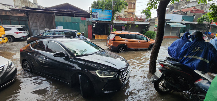Cơn mưa lớn khiến đoạn đường dài gần 300 mét đường tỉnh lộ 70 bị ngập lụt, các phương tiện bị chôn bánh.