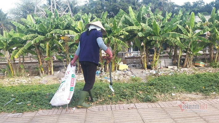 Trước cảnh khẩu trang vứt bỏ tràn lan trên đường Phạm Văn Đồng, nữ công nhân vệ sinh phải đi thu gom từng chiếc