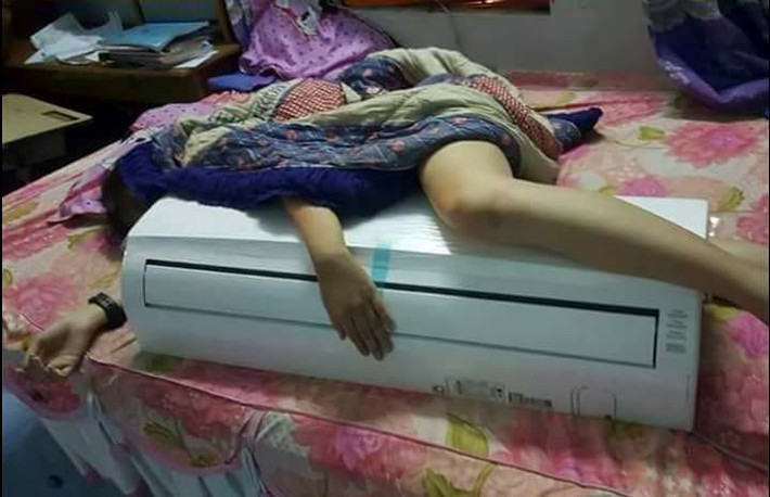 Đến khi đi ngủ cũng phải ôm chiếc điều hòa nhiệt độ. Cách chống nóng hài hước của cô gái này khiến dân mạng bật cười. Ảnh: Đỗ Xuân Định.