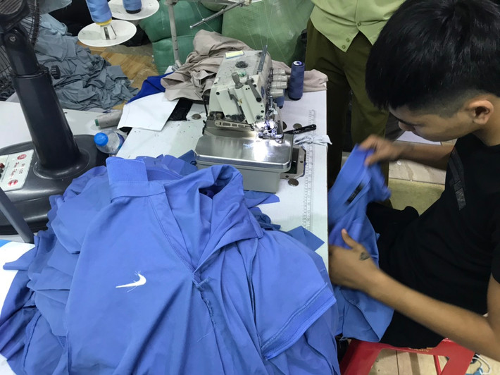 Hàng bán thành phẩm (vải đã được cắt thành khuôn thân hình áo phông nam, chưa được may thành phẩm trên mang các nhãn hiệu nhãn hiệu “hình NIKE”, “GUCCI và hình”, “LACOSTE và hình”) có số lượng 2.051 chiếc và nguyên liệu, vật liệu, công cụ dùng cho việc gia công, đóng gói các sản phẩm áo phông nam cộc tay mang nhãn hiệu “adidas và hình”, “hình NIKE”, “GUCCI và hình”, “LACOSTE và hình” gồm 11 kg cúc áo, 81 kg chỉ may các loại, 04 kg bao bì túi nilon, 04 chiếc máy may áo.