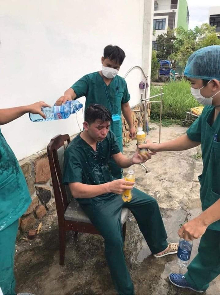 Trong khi đó, một số nhân viên khác lại được đồng nghiệp hỗ trợ uống nước, đổ nước ướt đẫm người cho tỉnh táo. Căng thẳng, áp lực là thế nhưng họ không cho phép mình gục ngã trong cuộc chiến chống COVID-19. Ảnh: Q.H.