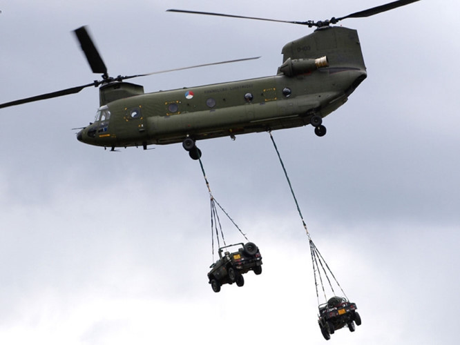 Một chiếc trực thăng CH-47 Chinook mang theo 2 xe quân sự.