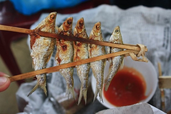 Cá nướng sông Đà: Những con cá tươi rói để nguyên con rồi dùng xiên từ đầu tới đuôi, dùng nẹp kẹp vào để cá khỏi bị rơi. Cá được nướng trên than hồng cho đến khi cháy xém, tỏa mùi thơm. Khi ăn chỉ cần rắc thêm một chút muối, rồi quấn vào trong lá chuối để một lúc là có thể ăn được. Ảnh: Danviet.