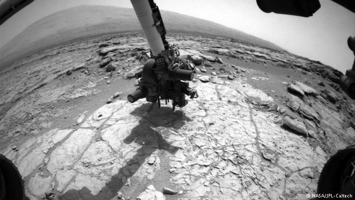 Cánh tay của Curiosity được trang bị máy khoan, giúp chiếc xe có khả năng thu thập các mẫu vật bên dưới bề mặt sao Hỏa. Hình ảnh chụp lại hoạt động thu thập mẫu vật tại miệng núi lửa Gale Crater năm 2013.