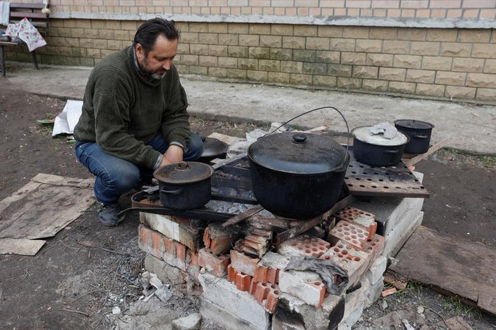 Cư dân địa phương nấu ăn trên một con phố ở Sievierodonetsk, vùng Luhansk, Ukraine, hôm 16/4.