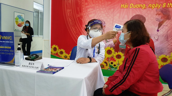 Kiểm tra y tế, đo thân nhiệt trước khi tiêm.