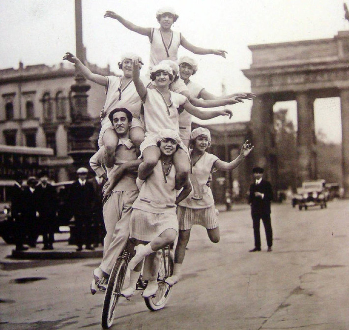 Một gia đình biểu diễn trên một chiếc xe đạp trên đường phố Berlin, Đức năm 1920. Màn trình diễn này thu hút sự chú ý của người dân xung quanh.
