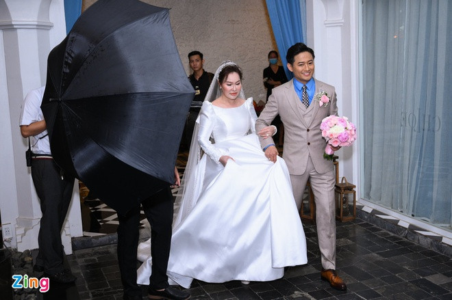Nam diễn viên rạng ngời cùng vợ tiến ra sân khấu. Cả hai được đội bảo vệ cầm dù, che chắn kỹ lưỡng trước khi ra chào quan khách.