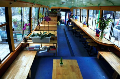 Bên trong ô tô là không gian 25 m2 được thiết kế độc đáo, thân thiện. Toàn bộ ghế cũ được tháo, thay vào đó là những chiếc bàn, ghế làm bằng gỗ.