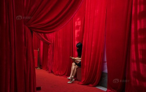 Nhiếp ảnh gia Cổ Quân Tùng đã ghi lại những khoảnh khắc chân thực nhất về “cuộc sống về đêm” ở ga xe lửa Vô Tích, Giang Tô, Trung Quốc. Nơi đây còn được mệnh danh là “Bar Street” hay còn gọi là “ con đường thác loạn”, “con đường ăn chơi” của thành phố Vô Tích. Trong ảnh, một gái làng chơi đang đợi điện thoại của khách quen.