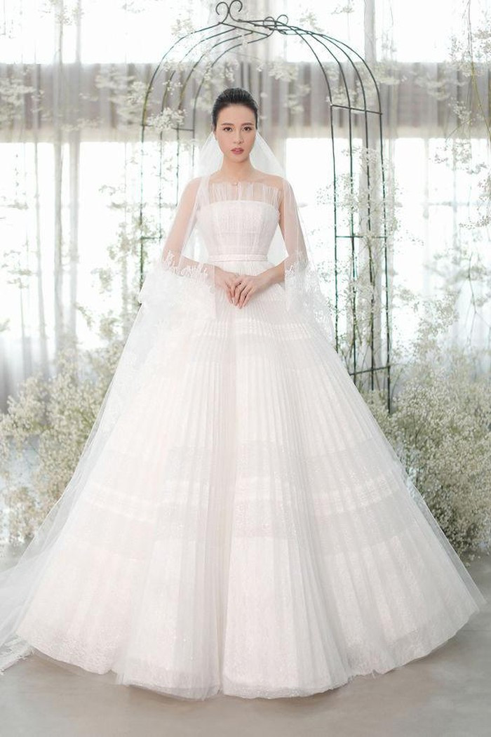 Điểm đặc biệt của chiếc váy cưới chính nằm ở kỹ thuật dựng phom corset giúp vòng eo nhỏ nhất có thể, đồng thời ở phần ngực áo, NTK chọn lựa dáng váy quây để tôn lên vòng một của cô dâu, nhấn nhá thêm lớp lưới dập ly khéo léo làm tăng thêm phần nền nã, dịu dàng. Ảnh: Saostar.
