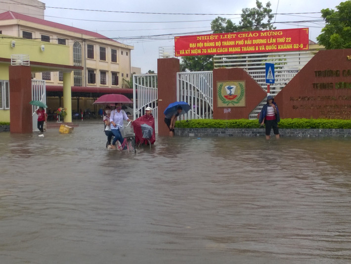 Học sinh, sinh viên khi tan học cũng vất vả đi lại do nước ngập sân trường, đường phố.