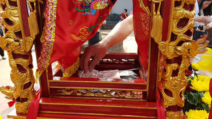 Nhiều người đặt tiền lẻ trong kiệu ấn.