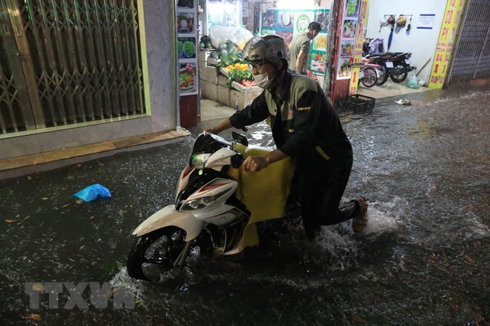 Nhiều người phải dắt xe qua đoạn ngập. (Ảnh: Tuấn Anh/TTXVN)