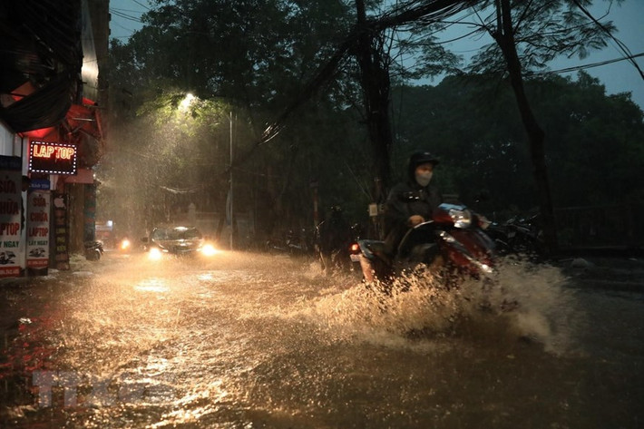 Do trận mưa lớn nên phố Khương Hạ ngập khiến nhiều người đi lại khó khăn. (Ảnh: Tuấn Anh/TTXVN)