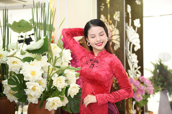 Vợ Chí Anh nổi bật với áo dài nhung đỏ bên sen trắng.