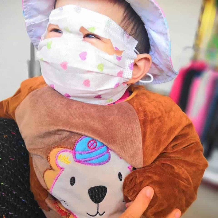 Vì kích cỡ những chiếc khẩu trang quá to, chỉ đeo đơn thuần thì cũng đã che cả mặt với trán của các bé rồi nên các phụ huynh đã cắt thành những lỗ để lộ phần mắt của bé.