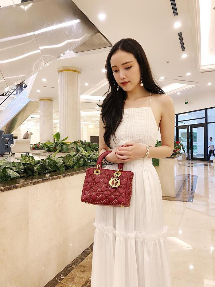 Mai Ngọc Phượng mặc chiếc đầm trắng hai dây đằm thắm mix với túi xách hàng hiệu màu đỏ sành điệu.