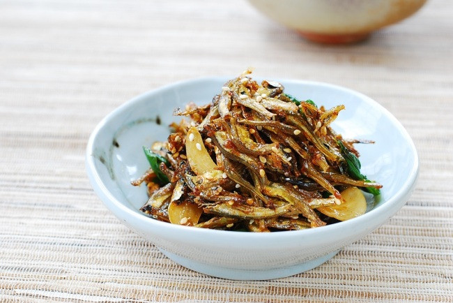Cá sau khi làm sạch, rán giòn, cho thêm các gia vị đã chuẩn bị vào đảo đều cho ngấm. Khi nước sốt còn sền sệt thêm hành lá , đảo đều là được. Ảnh: Keywordsuggestc