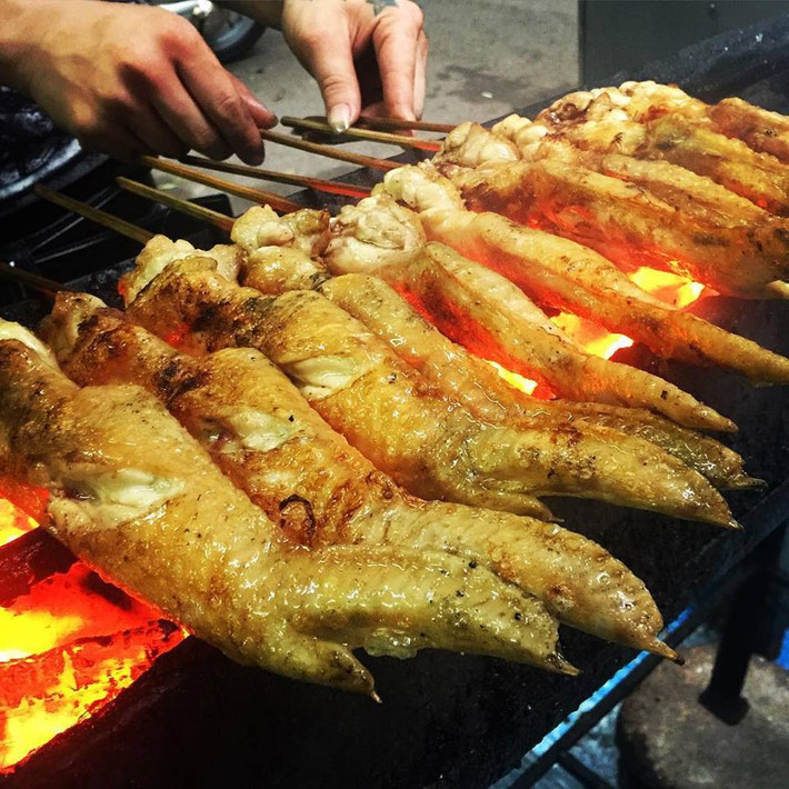 Cánh gà nướng than hoa: Để làm nên món gà này được chế biến khá đơn giản để giữ mùi thơm ngon tự nhiên của thịt gà. Khi chế biến người ta thường ướp cánh gà sau đó xiên que rồi nướng chín vàng trên than hoa. Món ăn thường được bán vào buổi chiều và tối ở các khu phố Gầm Cầu, phố chân gà nướng. Ảnh: Monngonmoingay.