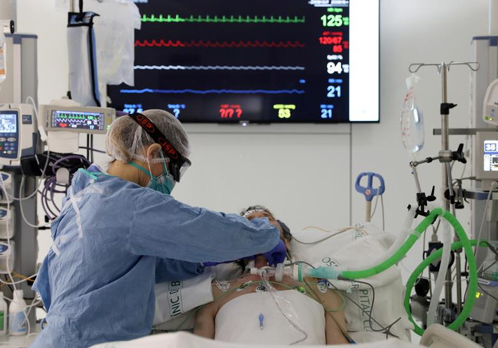 Nhân viên y tế điều chỉnh máy hỗ trợ hô hấp nhân tạo cho bệnh nhân COVID-19 ở bệnh viện Barcelona, Tây Ban Nha.