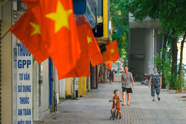 Trên những con đường rợp cờ hoa, cuộc sống dường như chậm lại. Người dân không vội vã mở cửa bán hàng như thường nhật, nhiều người đi bộ, ngắm cảnh, chụp ảnh phố xá yên bình. Hà Nội có những ngày bình yên khác lạ như thế. (Ảnh: GD&TĐ)