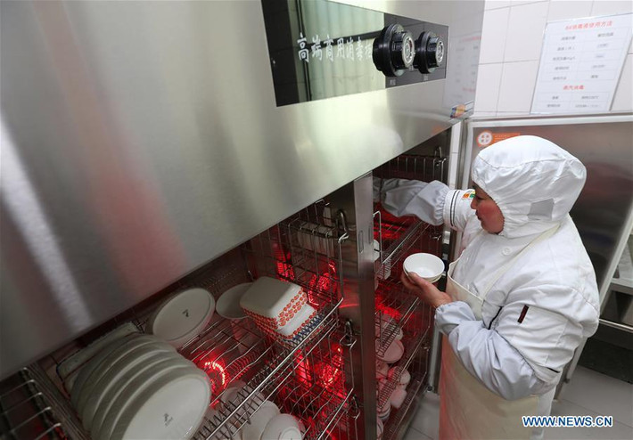 Một nhân viên đặt bát đĩa đựng suất ăn hàng không vào tủ khử trùng trong phòng ăn tại sân bay Nam Thông.