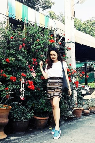 Nữ diễn viên trẻ chụp ảnh trong sân vườn tràn ngập hoa với chiếc ô tô đắt tiền "lấp ló" phía sau.