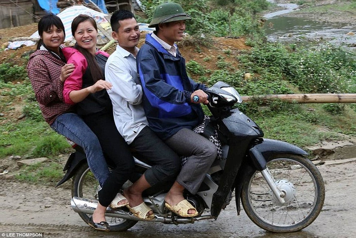 Chiếc xe máy chở quá tải di chuyển trên đường quê.