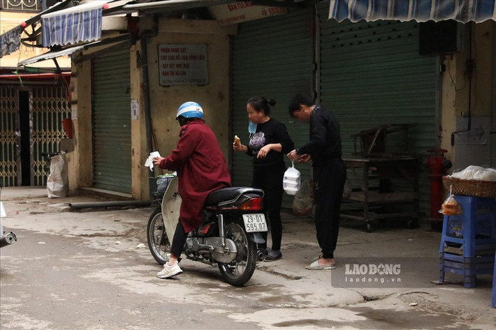 Ngay sát cổng chợ Khâm Thiên, 2 người trung niên vô tư không đeo khẩu trang khi nhận thực thẩm.