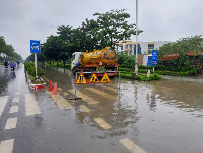 Làn xe máy, xe đạp của đường Trịnh Văn Bô bị ngập sâu, các phương tiện không thể di chuyển. Để bảo đảm an toàn, một chiếc xe bồn được bố trí chặn đường, không cho các phương tiện qua lại để chờ nước rút.