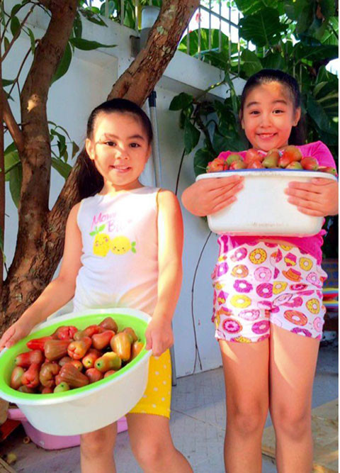 Hai cô con gái của MC Quyền Linh vui mừng thu hoạch trái trong vườn nhà. Ảnh: FBNV.