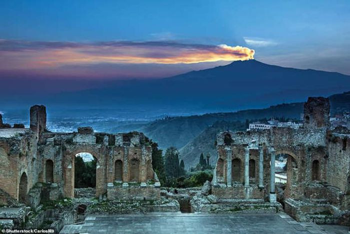 Bức ảnh tuyệt đẹp này cho thấy ngọn núi Etna ở Sicily, Italia thấp thoáng trên tàn tích của một nhà hát Hy Lạp cổ đại. Nó bắt đầu phun trào khoảng 500.000 năm trước, nằm dưới một tầng núi 35.000 năm tuổi.