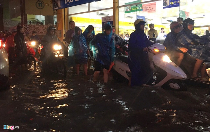 Trong ảnh là cảnh dắt xe máy trên phố Thái Hà (quận Đống Đa). Lúc này nước đã rút khá nhiều. Mưa đúng giờ tan tầm khiến nhiều người đi xe máy vất vả. Ảnh: Đức Phạm.