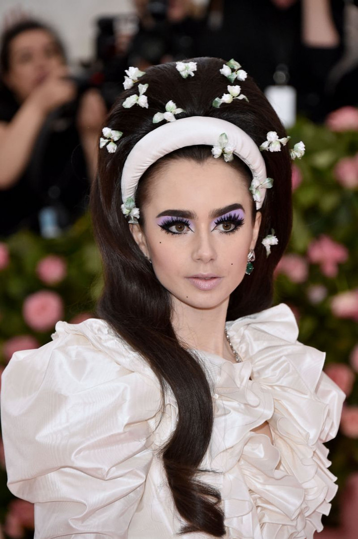 Lily Collins gây ấn tượng với khuôn mặt trang điểm trắng không tì vết được nhấn nhá với màu mắt tím và hàng eyeliner sắc lẹm.