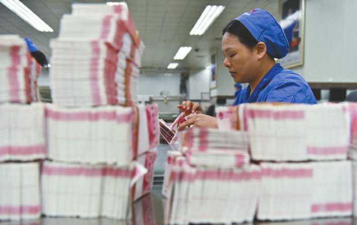 Một công nhân đang kiểm tra xấp tiền giấy mới in xong.