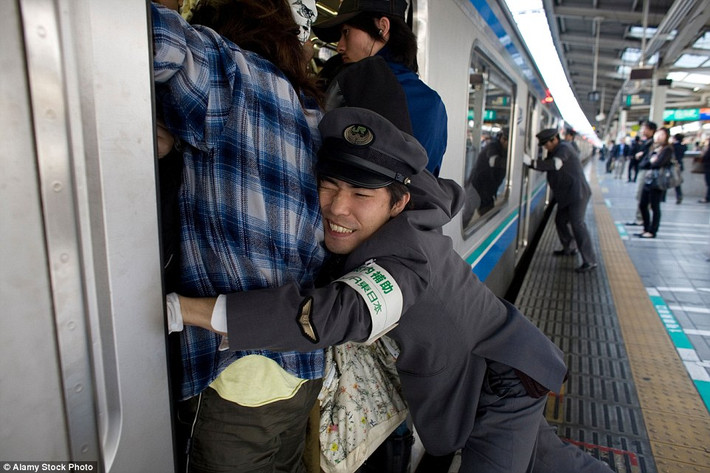 Nhân viên nhà ga Tokyo cố hết sức đưa hành khách vào bên trong đoàn tàu chật kín người để có thể đóng cửa để tàu chạy. Đây là một trong những nhà ga đông đúc nhất Nhật Bản vào giờ cao điểm luôn chật kín người.