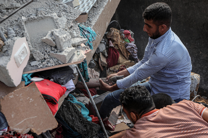Người đàn ông Palestine đau đớn nắm tay thân nhân thiệt mạng trong đống đổ nát ở Khan Younis, Gaza. Ảnh: Reuters.