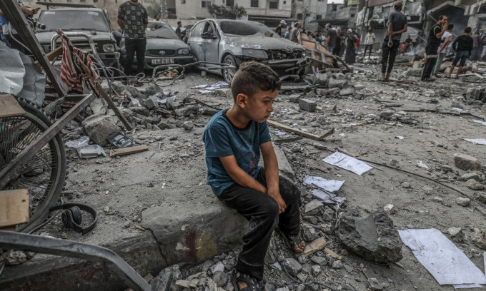 Bé trai ngồi bơ vơ giữa đống đổ nát của một tòa nhà bị phá hủy ở Khan Yunis, Dải Gaza, sau trận không kích của Israel. Ảnh: Reuters.