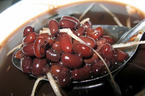 Cách làm: Đầu tiên, cho đậu đen vào nước ngâm khoảng 1 tiếng cho đậu nhanh mềm. Tiếp theo, bạn gọt vỏ dừa rồi dùng dao chặt miệng quả dừa nhưng nhớ giữ lại một phần sọ trên để làm nắp đậy. Ảnh: Monngonmoingay.
