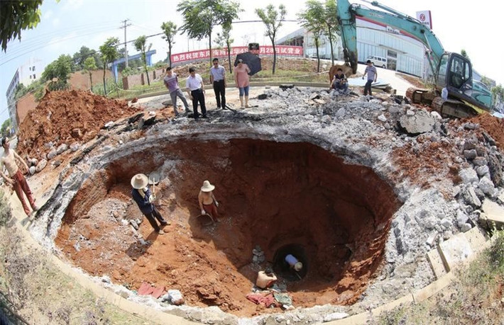 Một đội cứu hộ làm việc dưới khu vực bị sụt lún do "hố tử thần" gây ra trên một con đường ở Loudi, tỉnh Hồ Nam, Trung Quốc vào ngày 18/6/2013.Ảnh: Reuters.