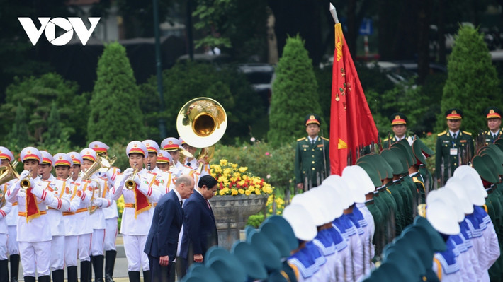 Thủ tướng Phạm Minh Chính và Thủ tướng Đức Olaf Scholz thực hiện nghi thức chào quân kỳ Việt Nam.