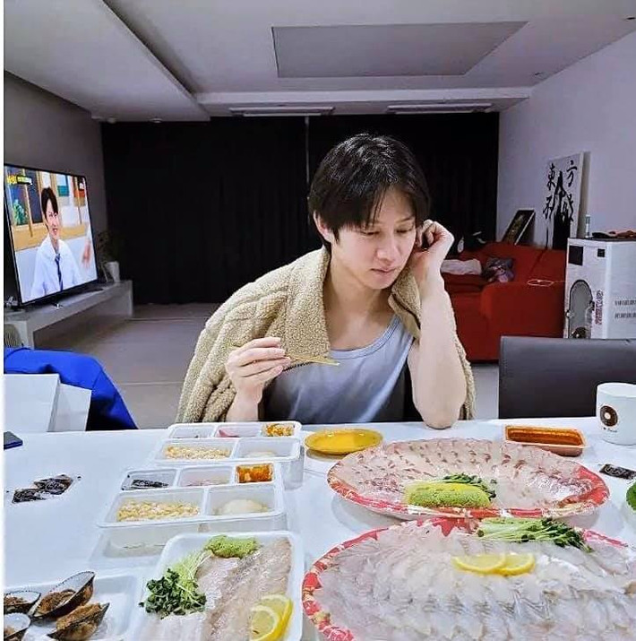 Một Kim Hee Chul đang ăn và một Kim Hee Chul trên màn hình tivi phía sau