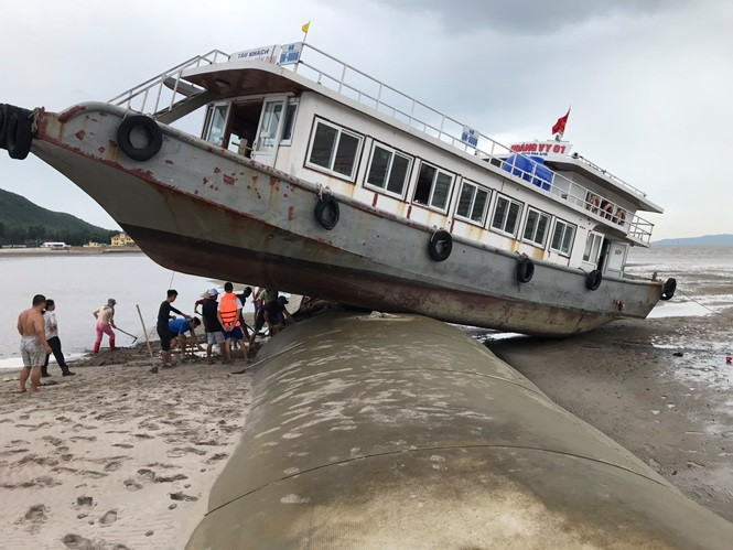 Theo chủ tàu, thuyền trưởng là người địa phương nhưng do trời tối và khu vực dự án lấn biển này không hề có biển cảnh báo nên tàu Hoàng Vi 1 đã chạy thẳng lên đê bao và mắc kẹt tại đây. Sau khi thủy triều rút đi, mũi tàu hếch hẳn lên hàng mét so với đuôi tàu. Trong ảnh: Hàng chục người được huy động cùng máy móc để đào cát hạ mũi tàu xuống chờ thủy triều lên.