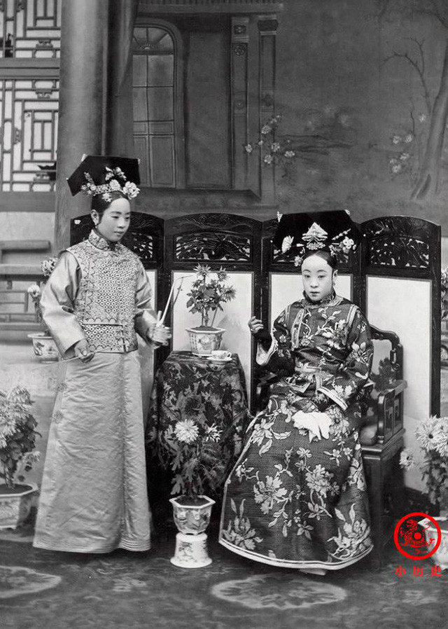 Người đang ngồi là mẹ ruột của Hoàng đế Phổ Nghi, vị Hoàng đế cuối cùng của nhà Thanh và cũng là Hoàng đế cuối cùng của chế độ phong kiến Trung Hoa. Cô gái bên trái là gia nhân của bà, đang hầu hạ bà uống trà.